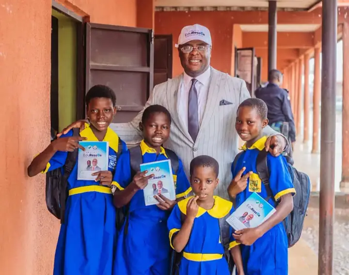 Dr Paddy Iyamu with four pupils holding Project EduRescue exercise books