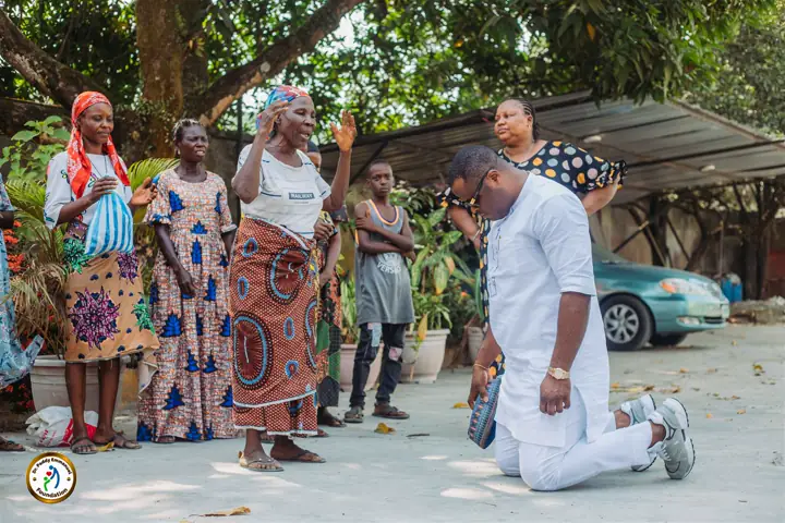 Kneeling to greet beneficiaries