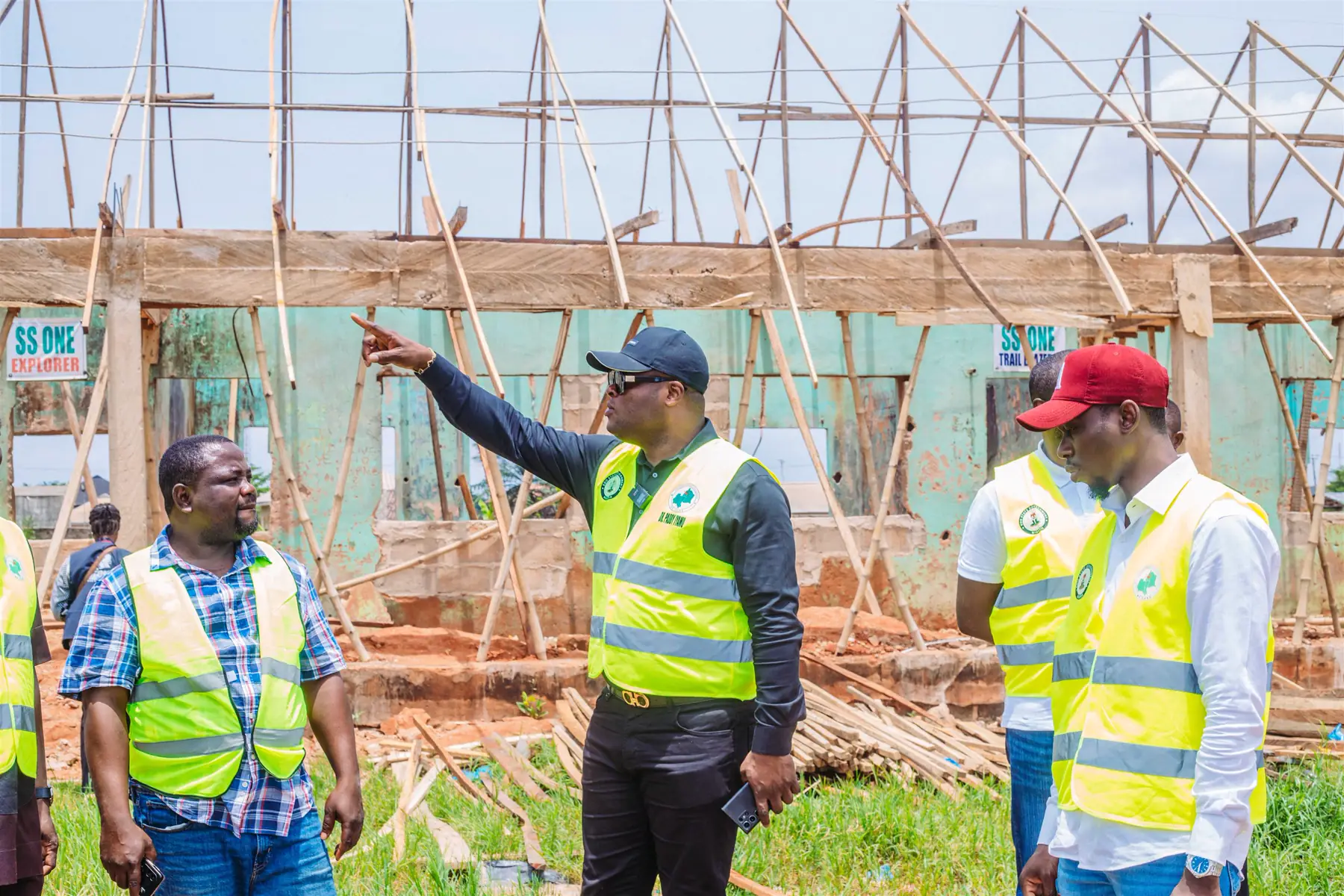 Dr Paddy Iyamu in a safety vest pointing out work at a school construction site