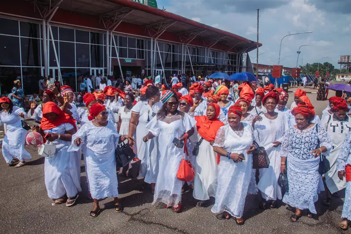 Women in white and red walking in a procession in Benin City